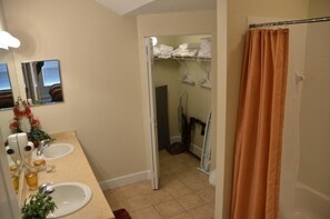 A bathroom with two sinks, a shower curtain, and a walk-in closet with shelves. - Lucaya 3 Bedroom 2 Bath First Floor Townhome (Kissimmee)