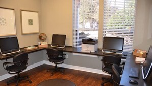 Oficina profesional con cuatro escritorios, cada uno con una computadora y una silla. Hay cuadros en la pared, un globo terráqueo e una impresora.