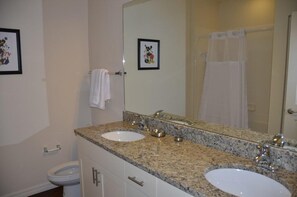 A bathroom with two sinks, a large mirror, and a toilet.