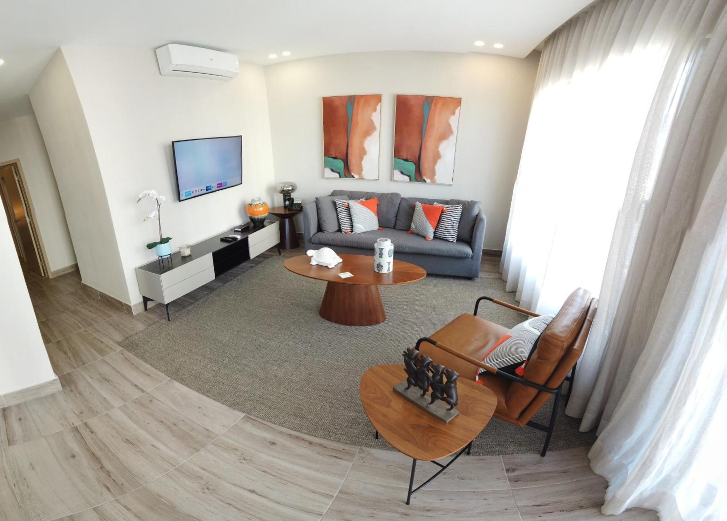 Ein modernes Wohnzimmer mit einem grauen Sofa, einem Couchtisch und einem an der Wand montierten Fernseher.