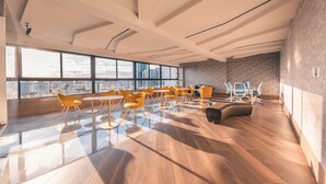Une pièce spacieuse avec de grandes fenêtres, un plancher en bois et des chaises jaunes.