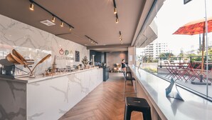 Un espace bar moderne doté d’un comptoir en marbre, de planchers en bois et offrant une vue sur la ville grâce à de grandes fenêtres.