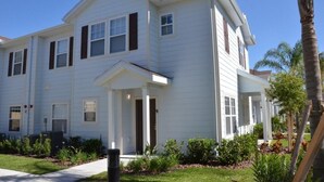 A two-story white house with a front porch, multiple windows, and a well-maintained garden. - Modern Lucaya 4 Bedrooms 3 Baths Townhome (Kissimmee)