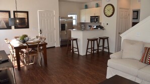 A spacious living room with a white sofa and a dining area with wooden furniture. - Modern Lucaya 4 Bedrooms 3 Baths Townhome (Kissimmee)