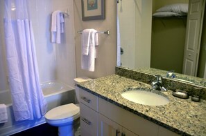 A bathroom with a granite sink, a toilet, a shower curtain, and a towel rack. - Lucaya 4 Bedrooms 3 Baths Family Friendly Townhome (Kissimmee)