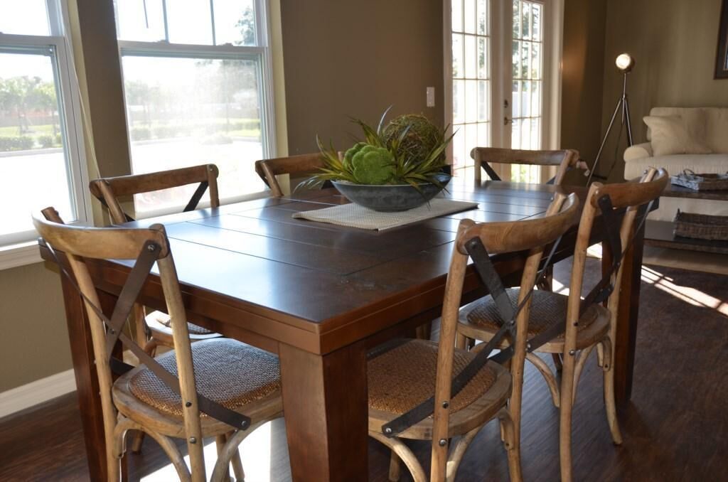 A dining area with a wooden table and four chairs, a bowl with plants, and a lamp.