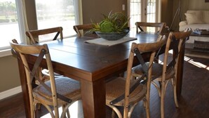 A dining area with a wooden table and four chairs, a bowl with plants, and a lamp.