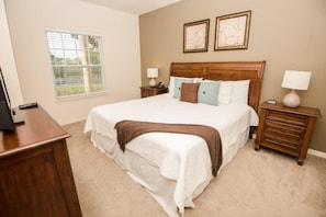 A bedroom with a large bed, two bedside tables, a nightstand, a window, and two wall-mounted pictures. - December Special LV 3 Beds 2 Baths Id:61208 (Kissimmee)