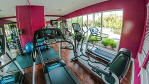 A gym with treadmills, elliptical machines, and exercise balls.