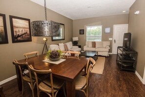 A dining area with a wooden table and chairs, a hanging light fixture, and a sofa in the background. - December Special LV 3 Beds 2 Baths Id:61208 (Kissimmee)
