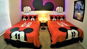 Un dormitorio con dos camas, cada una con ropa de cama temática de Mickey Mouse.