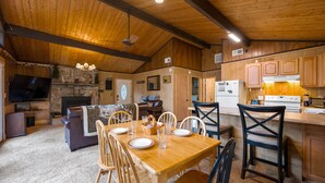 A cozy, wood-paneled interior with a dining area, kitchen, and living room.