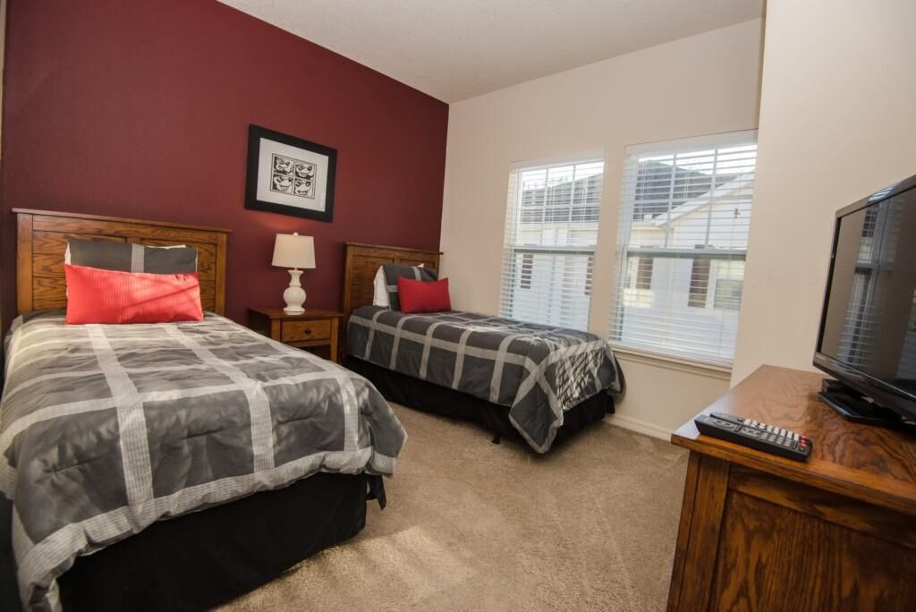 A bedroom with two beds, a TV, and a window.