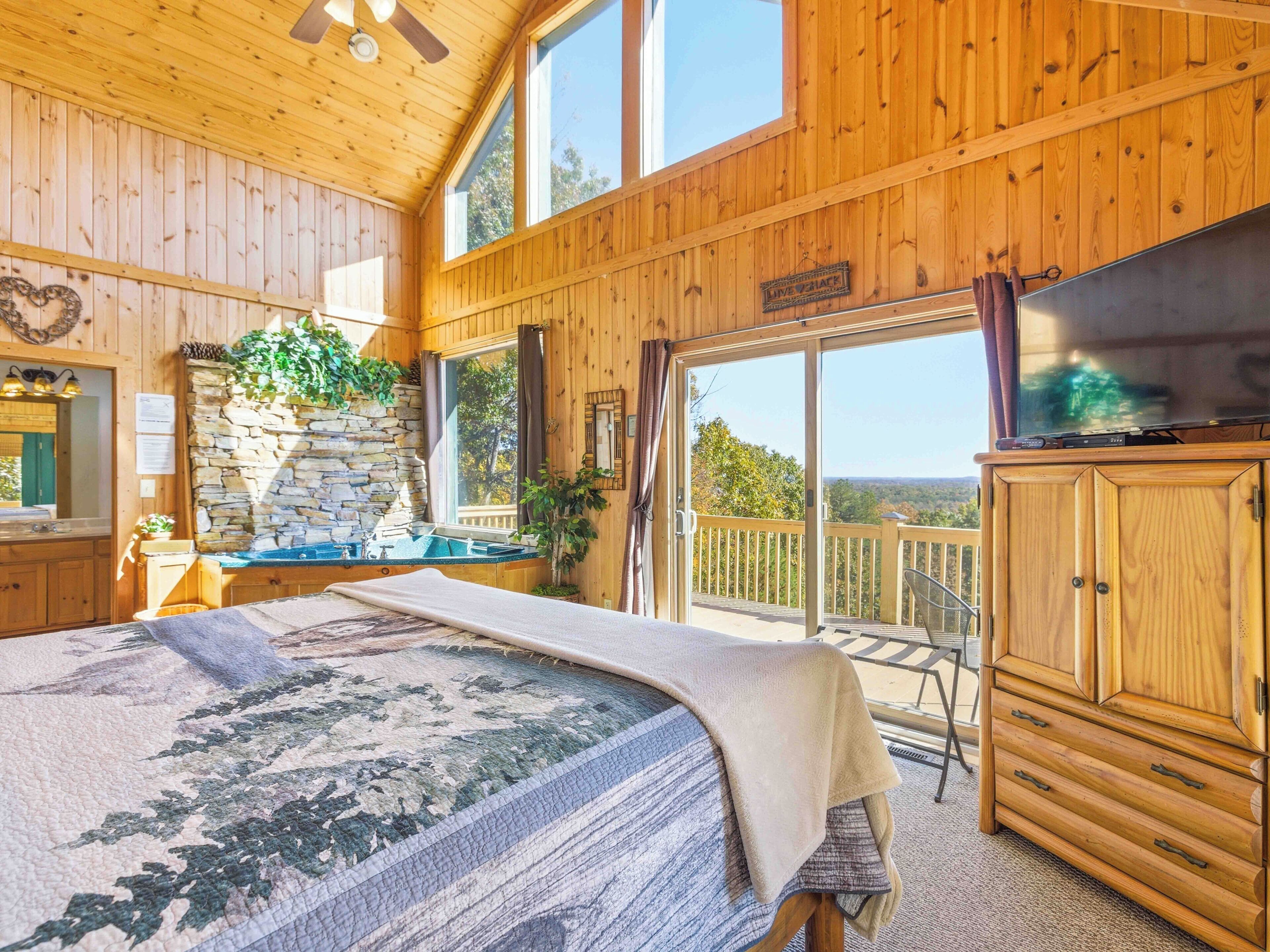Een houten hut met een groot bed, een stenen muur, een stenen wastafel en een balkon met uitzicht.
