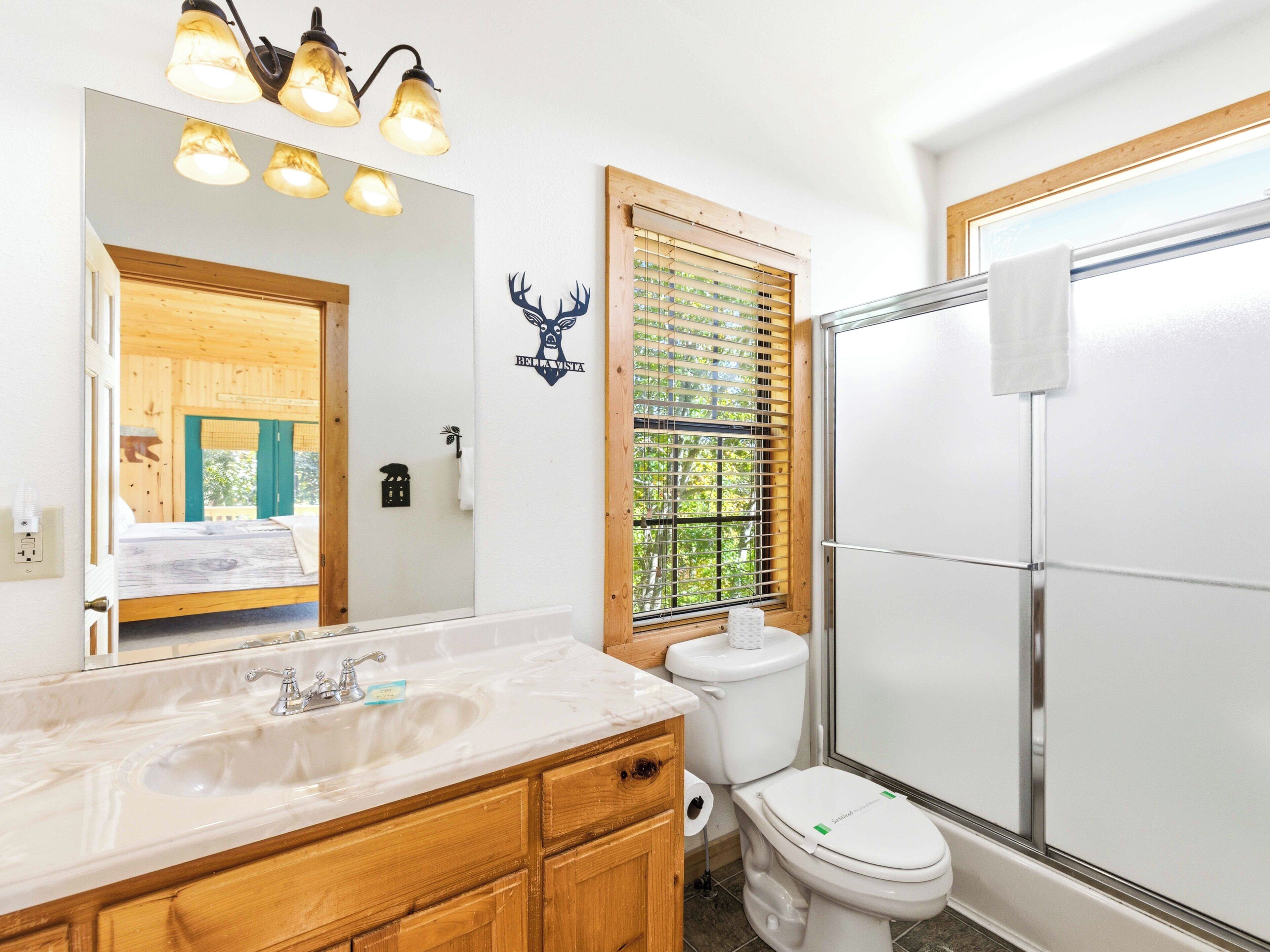 A bathroom with a wooden vanity, a sink, a toilet, and a shower.