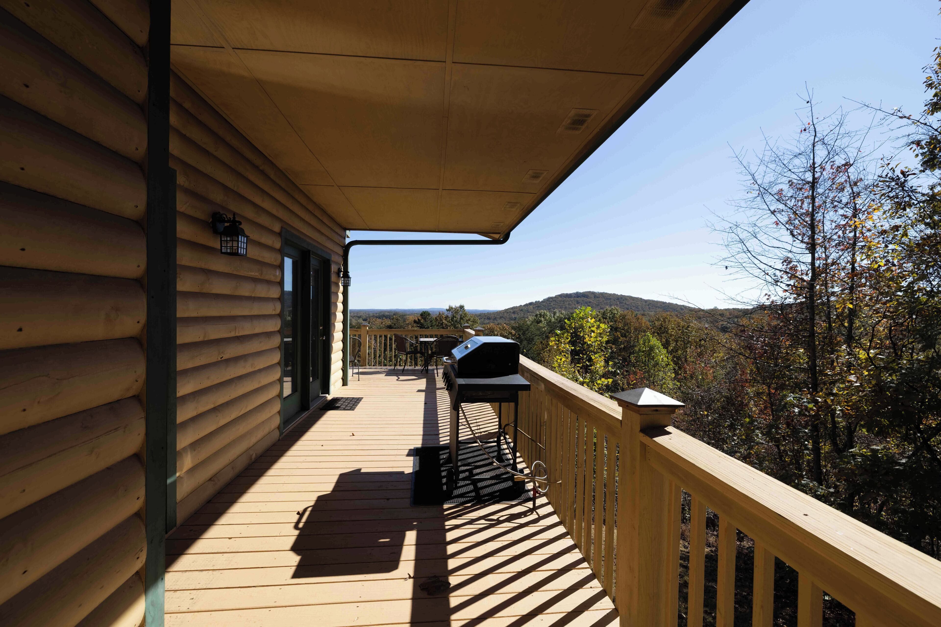 A wooden deck with a barbecue grill and a view of the surrounding landscape.