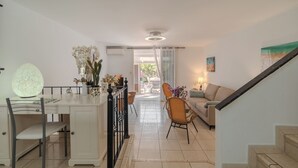 Una cocina moderna con comedor, una escalera y una sala de estar con sofá y lámpara.