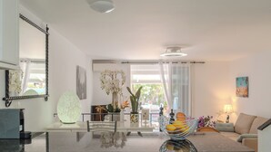 Una cocina moderna con encimera de mármol, armarios blancos y un comedor con mesa de vidrio.