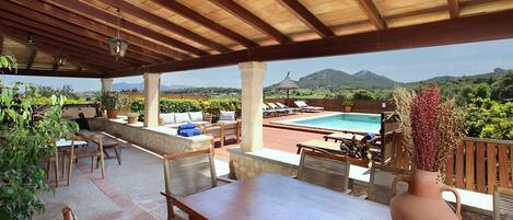 An outdoor patio with a pool, wooden furniture, and a view of mountains.