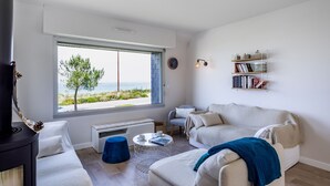 Un salon moderne avec une grande fenêtre, une cheminée, un canapé, une table basse et une bibliothèque.