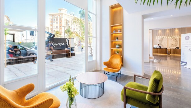 A modern hotel lobby with large windows, a reception desk, and seating areas. - Soho Boutique Equitativa (Málaga)