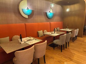 A restaurant interior with booths, tables, and chairs. - Petit Palace La Equitativa formerly known as Soho Boutique Equitativa (Málaga)