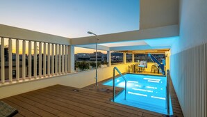 A rooftop pool area with a wooden deck, a pool with a metal ladder, and a view of the cityscape in the background. - Soho Boutique Equitativa (Málaga)