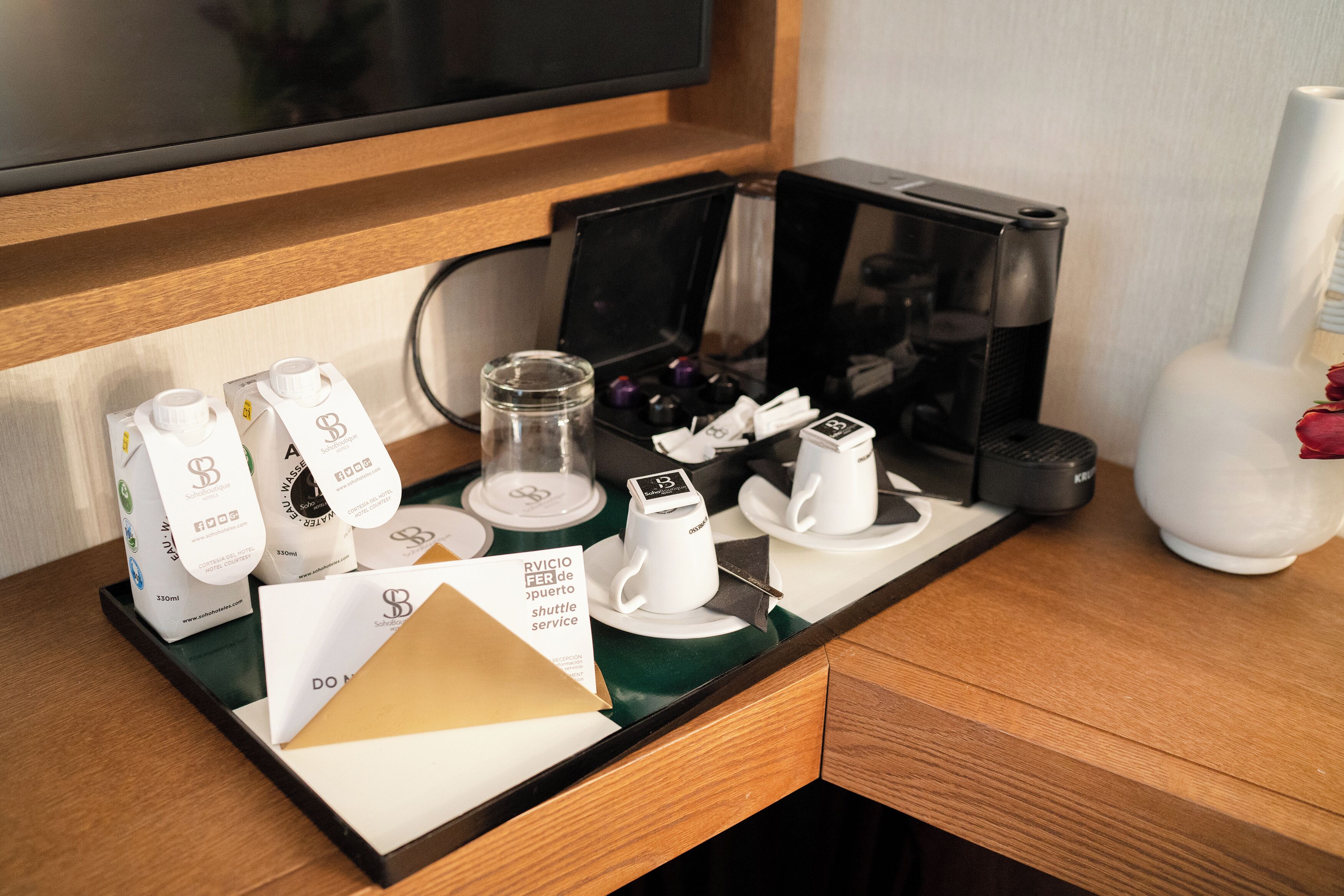 Un miniibar de hotel con una cafetera, un juego de té y una botella de agua.