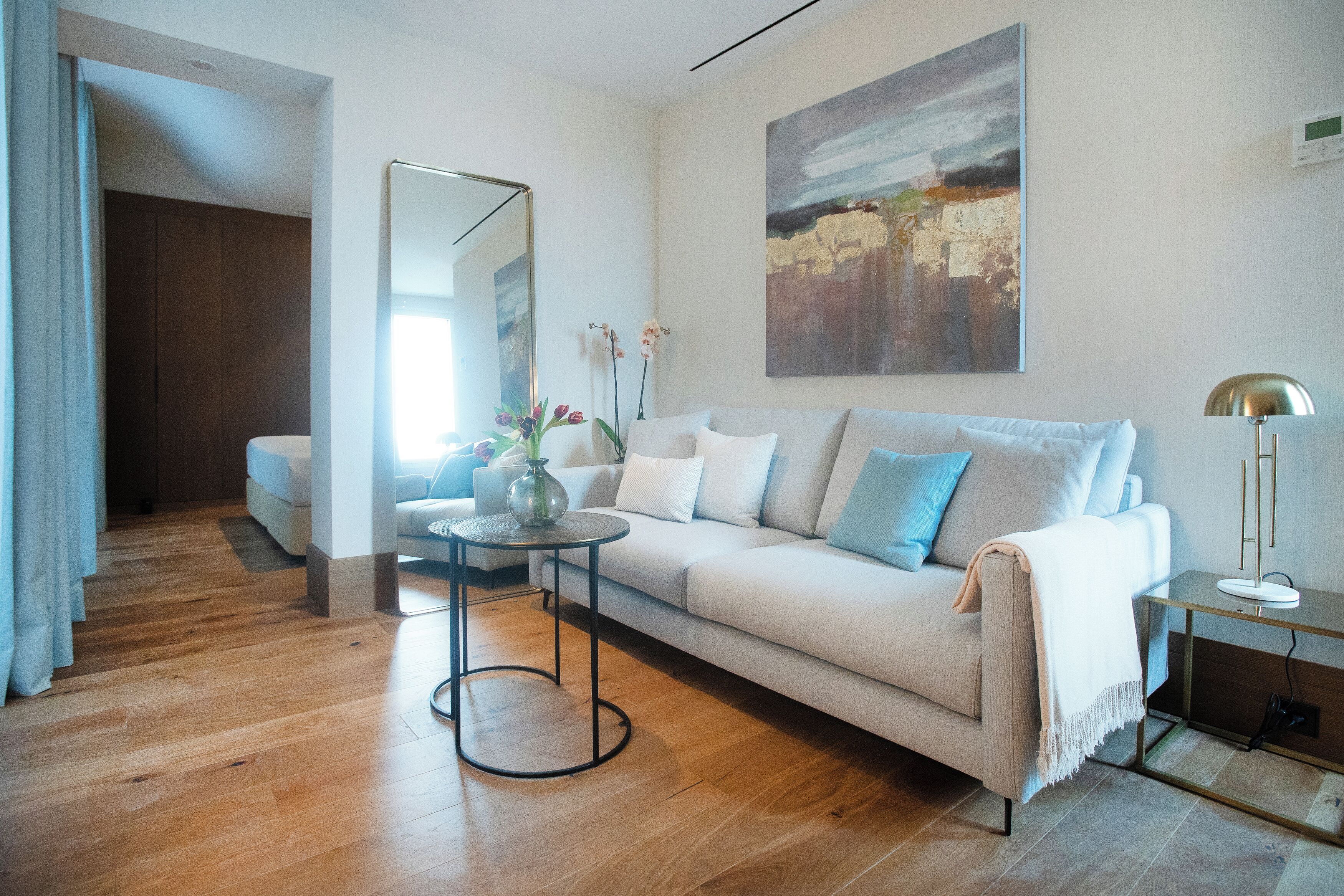 A modern living room with a sofa, a coffee table, and a painting on the wall.