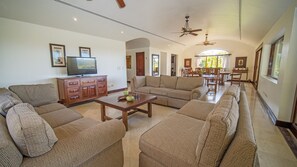 A spacious living room with a large sectional sofa, a wooden coffee table, and a television on a cabinet.
