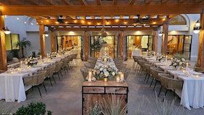 Un comedor interior con varias mesas dispuestas para una comida, vigas de madera en el techo y una pieza decorativa central.