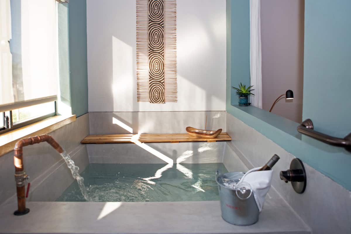 A bathtub with a wooden tray, a bucket, and a towel.