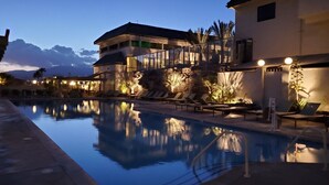 Zona de piscina con sillones de descanso y un edificio de varios pisos con ventanas amplias.