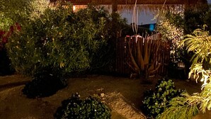 Una estructura con techo de paja, con un jardín delantero, rodeada de follaje denso.