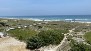 A coastal path leading to a beach with a wooden walkway and sparse vegetation.