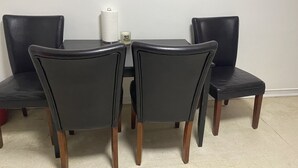 A dining table with four chairs, a tissue roll, and a candle with the text "Never stop believing."