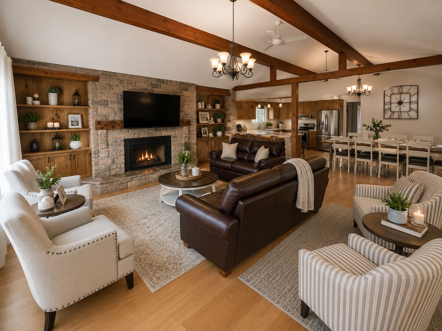 A spacious living room with a fireplace, leather sofas, a flat-screen TV, wooden beams, and a dining area.