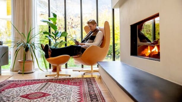 A modern living room with a large window, a fireplace, and a comfortable seating area. - Lindstrøm Hotel (Laerdal)