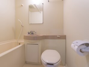 Een kleine badkamer met toilet, wastafel en bad.