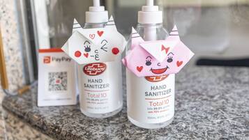 Twee desinfecterende handgel flessen met kattengezichtjes op een aanrecht.