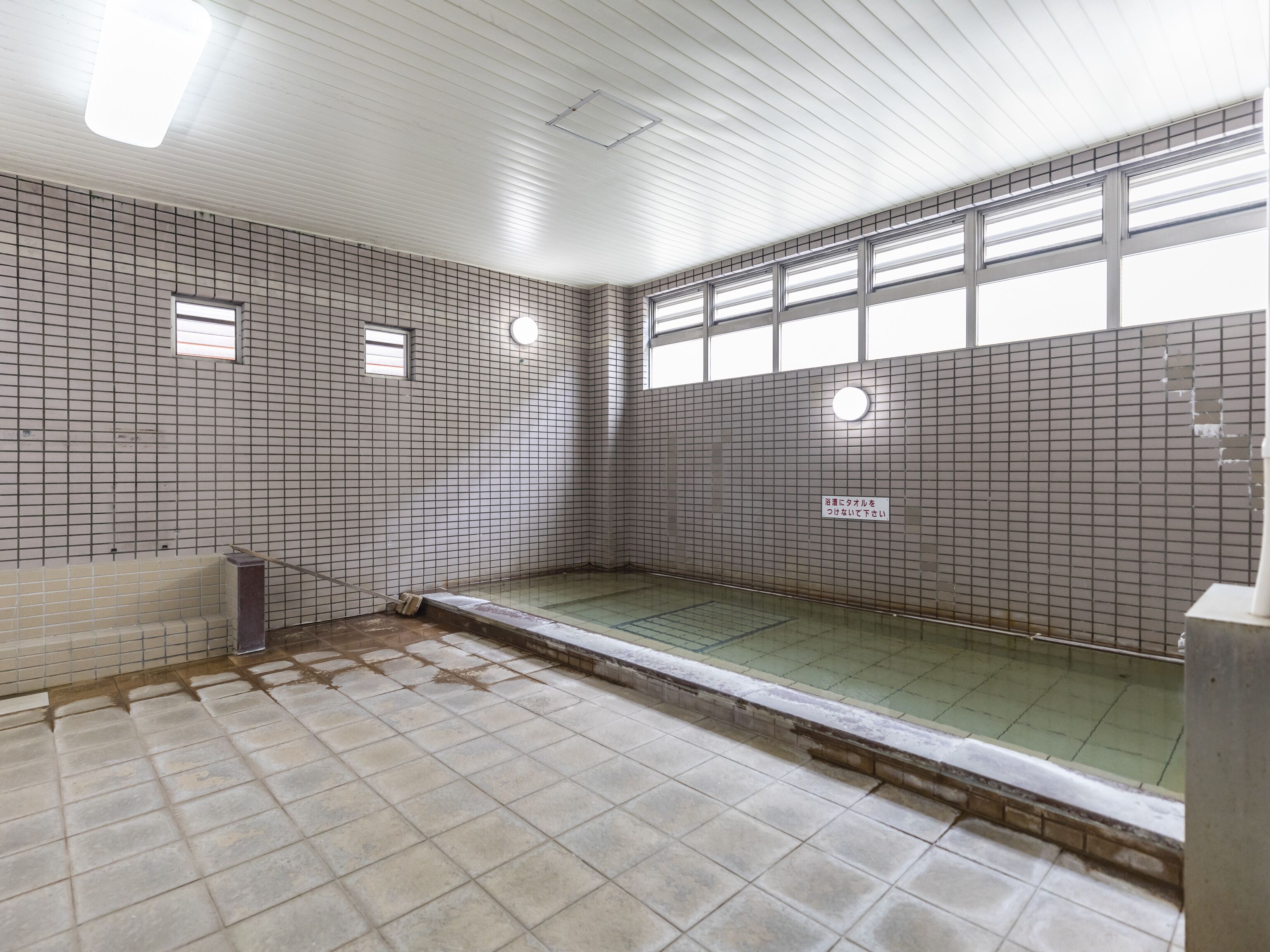 Ein gefliestes Badezimmer mit einer Badewanne, einer Duschkabine und einem Fenster.