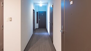 Pasillo de hotel con puertas numeradas 502 y 505, una lámpara en el techo y suelo alfombrado.