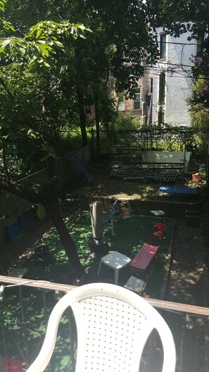Une cour avec des sièges extérieurs, une aire de jeux et un bâtiment en arrière-plan.