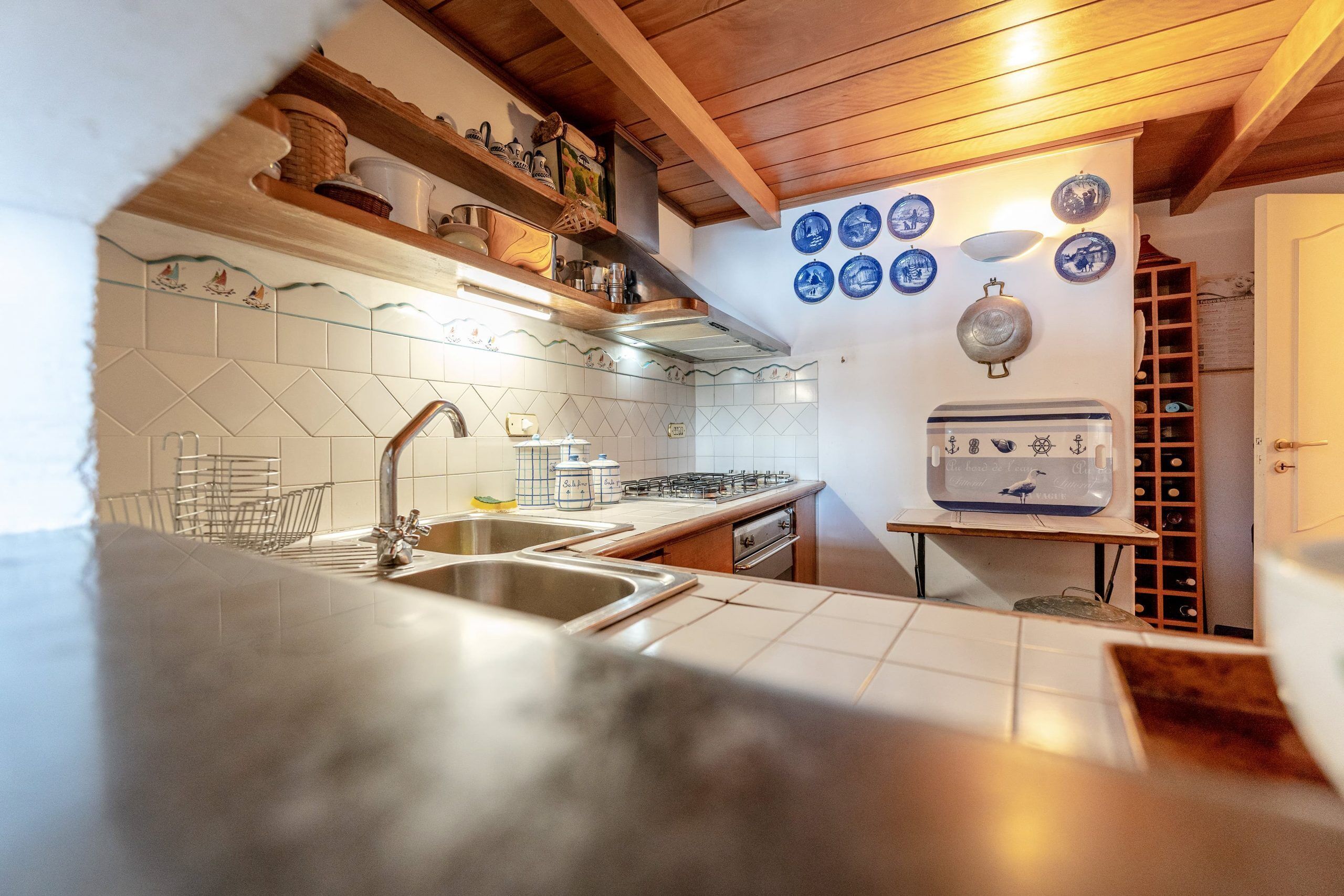 A kitchen with a double sink, a gas stove, and a wine rack.