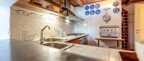 A kitchen with a double sink, a gas stove, and a wine rack.