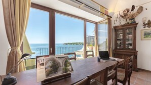 Zona pranzo con vista mare, un laptop sul tavolo e un mobile con oggetti decorativi.