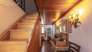 Una scala in legno conduce a un pianerottolo con una panchina e lampade a parete.