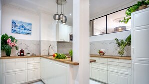 A modern kitchen with white cabinets, a marble backsplash, and a painting of a building. - Charming 100m² with 3BR - Romantic City Center (Paris)