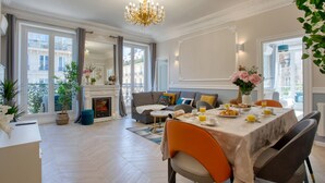 A dining area with a table set for breakfast, a sofa, and a fireplace. - Charming 100m² with 3BR - Romantic City Center (Paris)