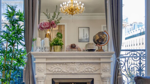 A luxurious living room with a fireplace, a large mirror, and a view of the city. - Charming 100m² with 3BR - Romantic City Center (Paris)